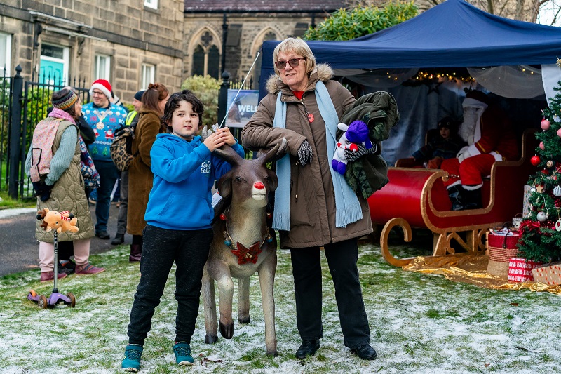 Boy and woman stand next to model of Rudolph Red Nosed Reindeer at Horsforth Christmas Lights switch on event